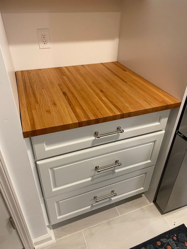A kitchen with white cabinets and a wooden counter top.