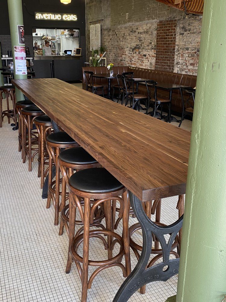 A restaurant with a long wooden table and stools