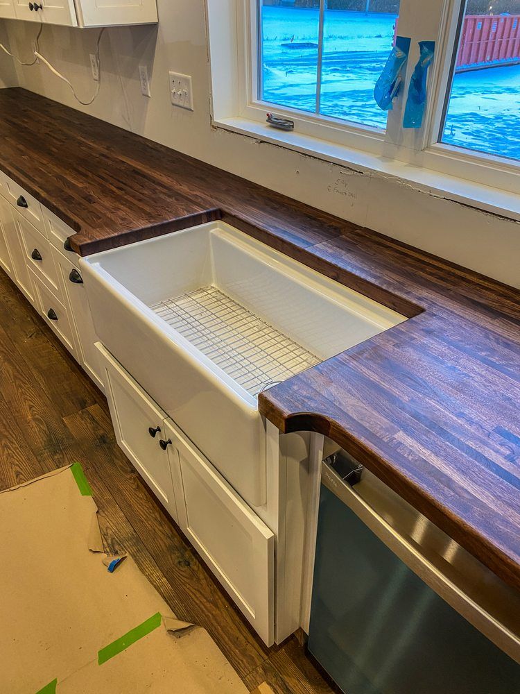 A kitchen with a white sink and wooden counter tops.