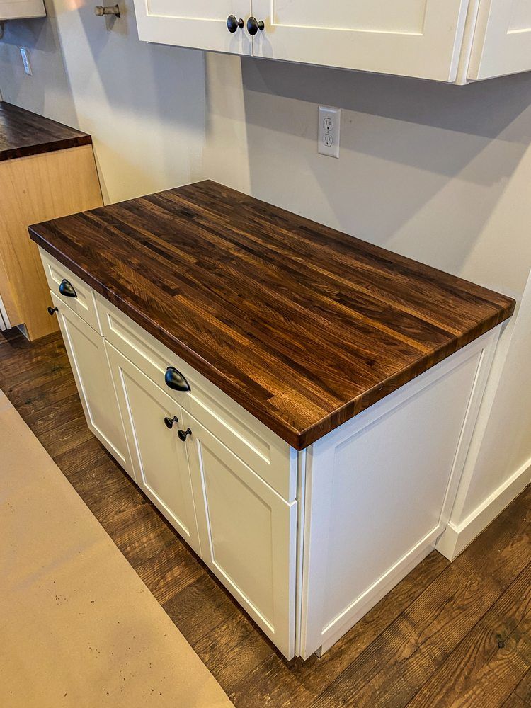 A kitchen island with a wooden counter top and white cabinets.