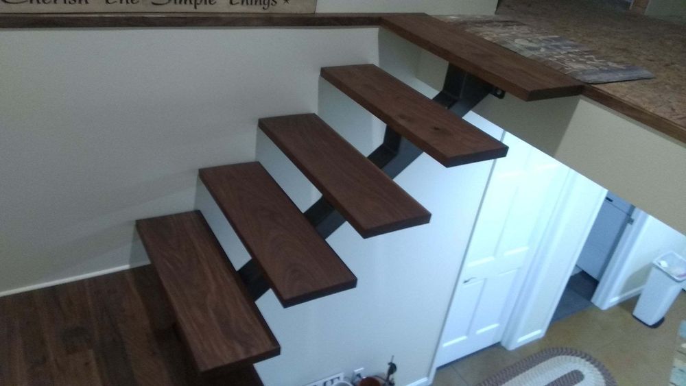 A wooden staircase in a room with a white wall