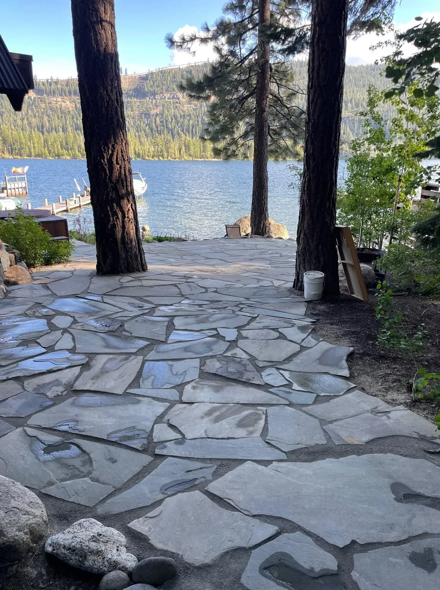 Stone pathway leading to a lake, with trees on either side.