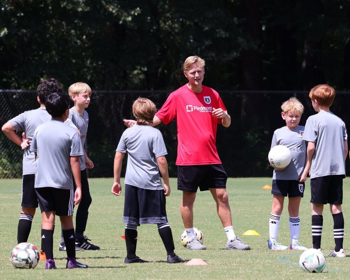 A soccer coach mentoring a young player on the field
