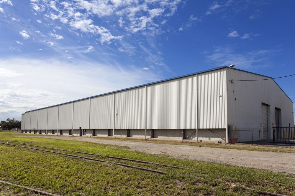 A Large White Building is Sitting in the Middle of a Grassy Field — Urbon Sheds in Casino, NSW