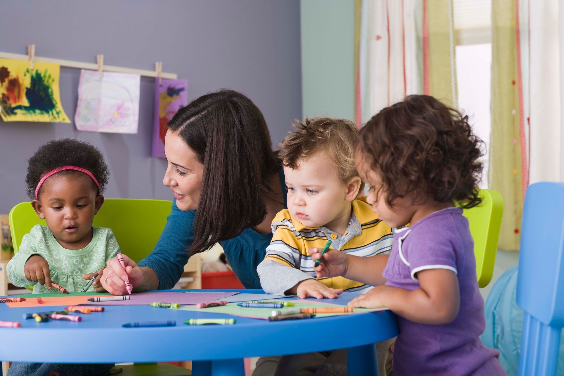 Kids Kampus daycare in Wheaton, IL. Teacher engaging with toddlers in a colorful classroom, 
