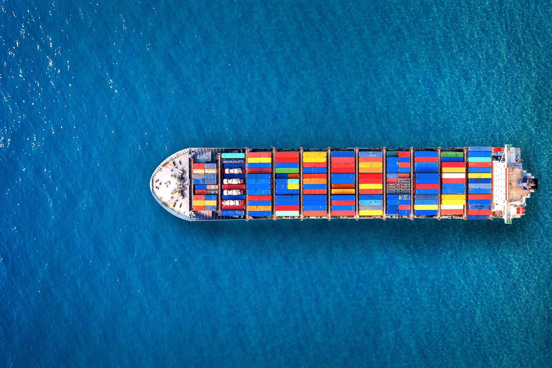 Large cargo ships docked at a port with yellow cranes under a clear, blue sky.