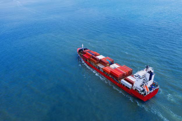 Red cargo ship sailing on blue ocean.