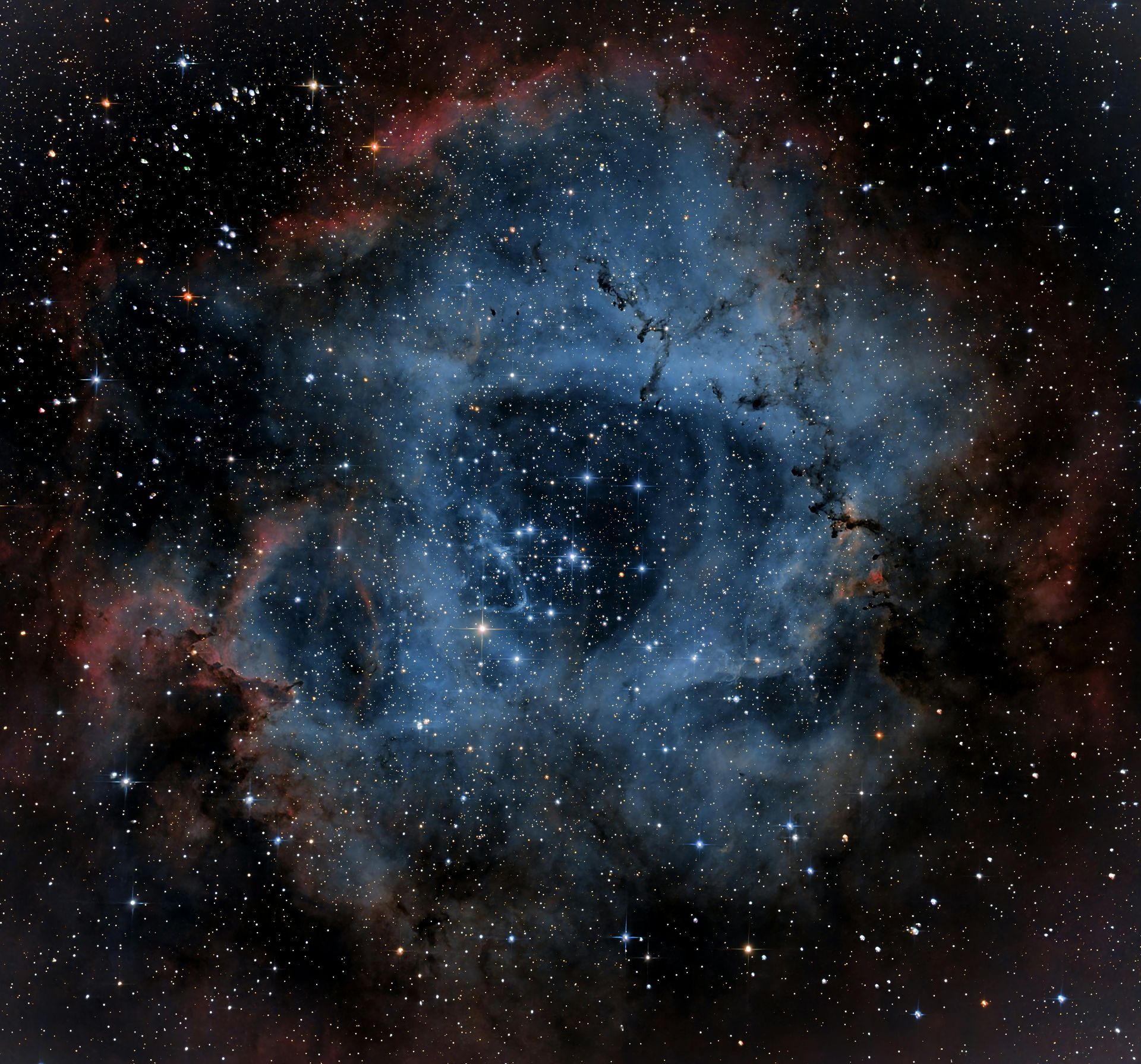 Rosette Nebula: A blue and red interstellar cloud with bright stars at the center.