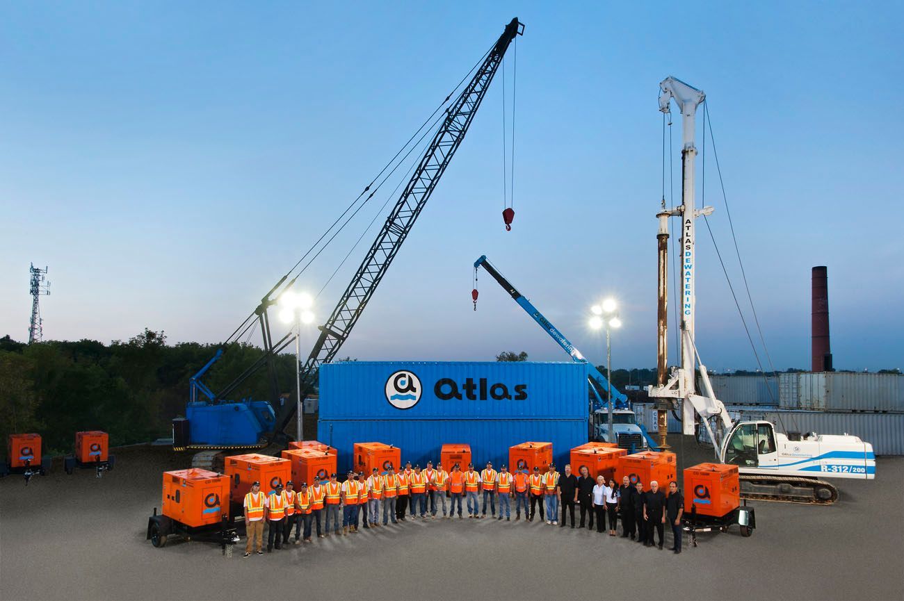 Construction site with Atlas equipment, a team of workers, cranes, and generators.