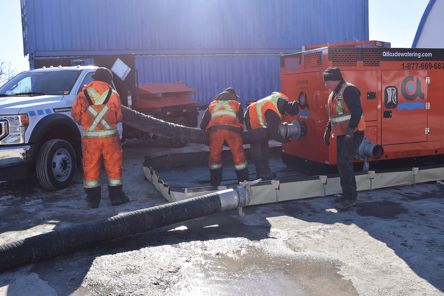 Two men in work clothes, one in red, the other in blue, work on machinery outdoors.