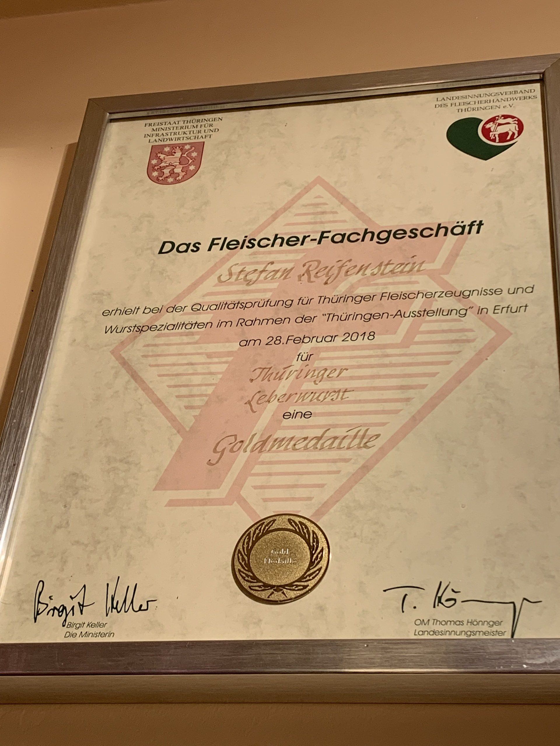 An der Wand hängt eine gerahmte Urkunde.