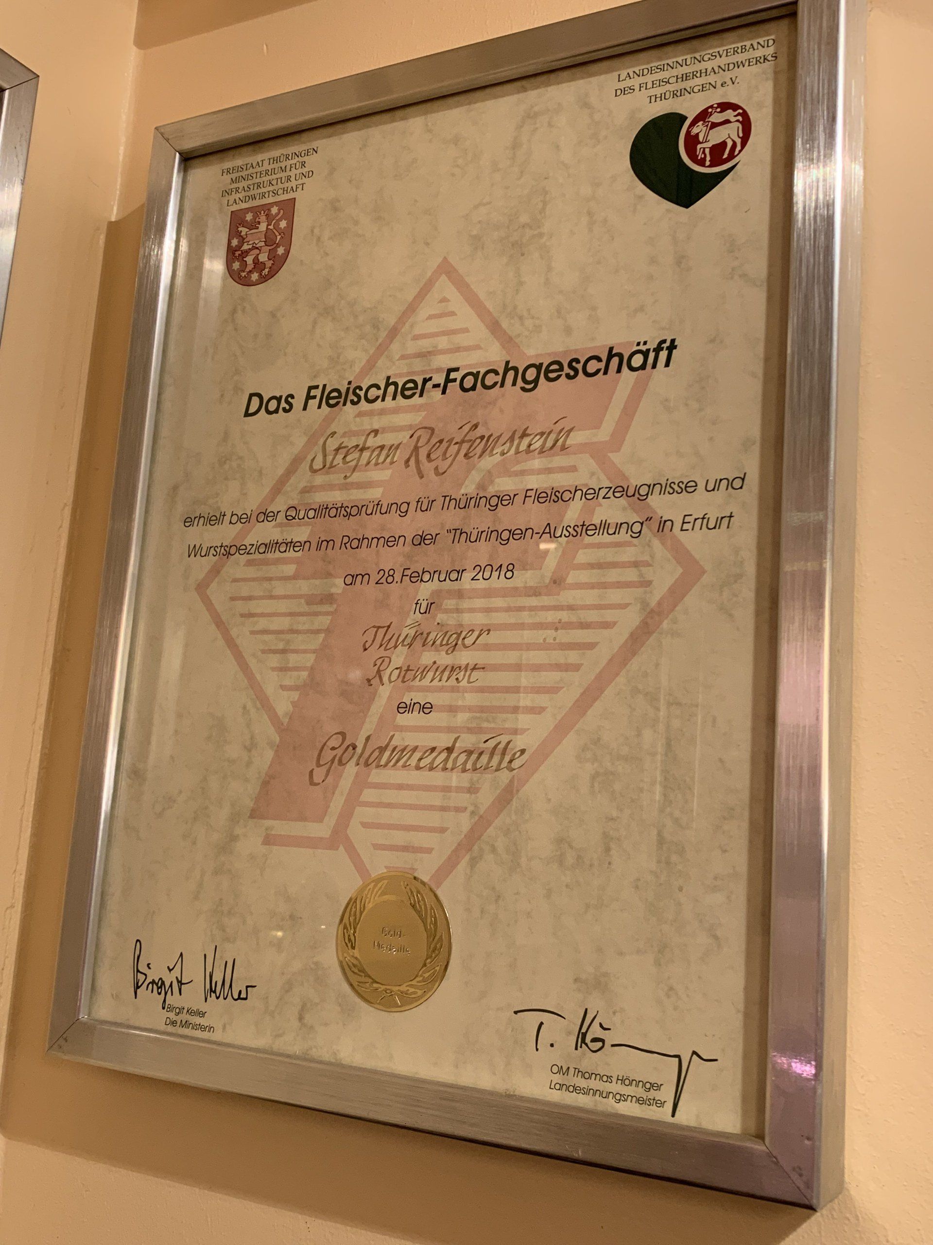 An der Wand hängt eine gerahmte Urkunde.