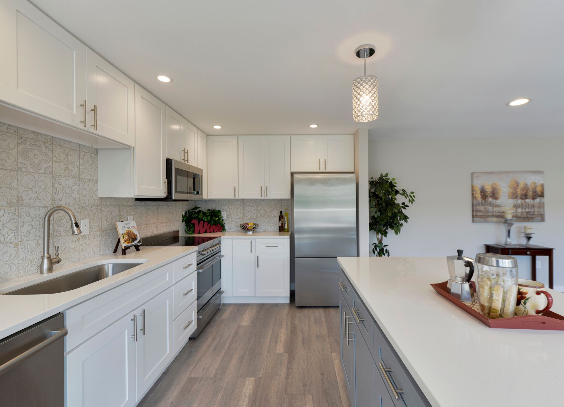 Cuisine moderne avec armoires blanches, électroménagers en acier inoxydable et îlot gris.