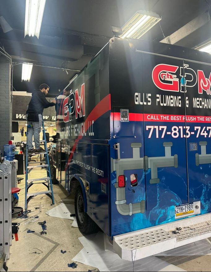 A man is standing on a ladder next to a gpm truck