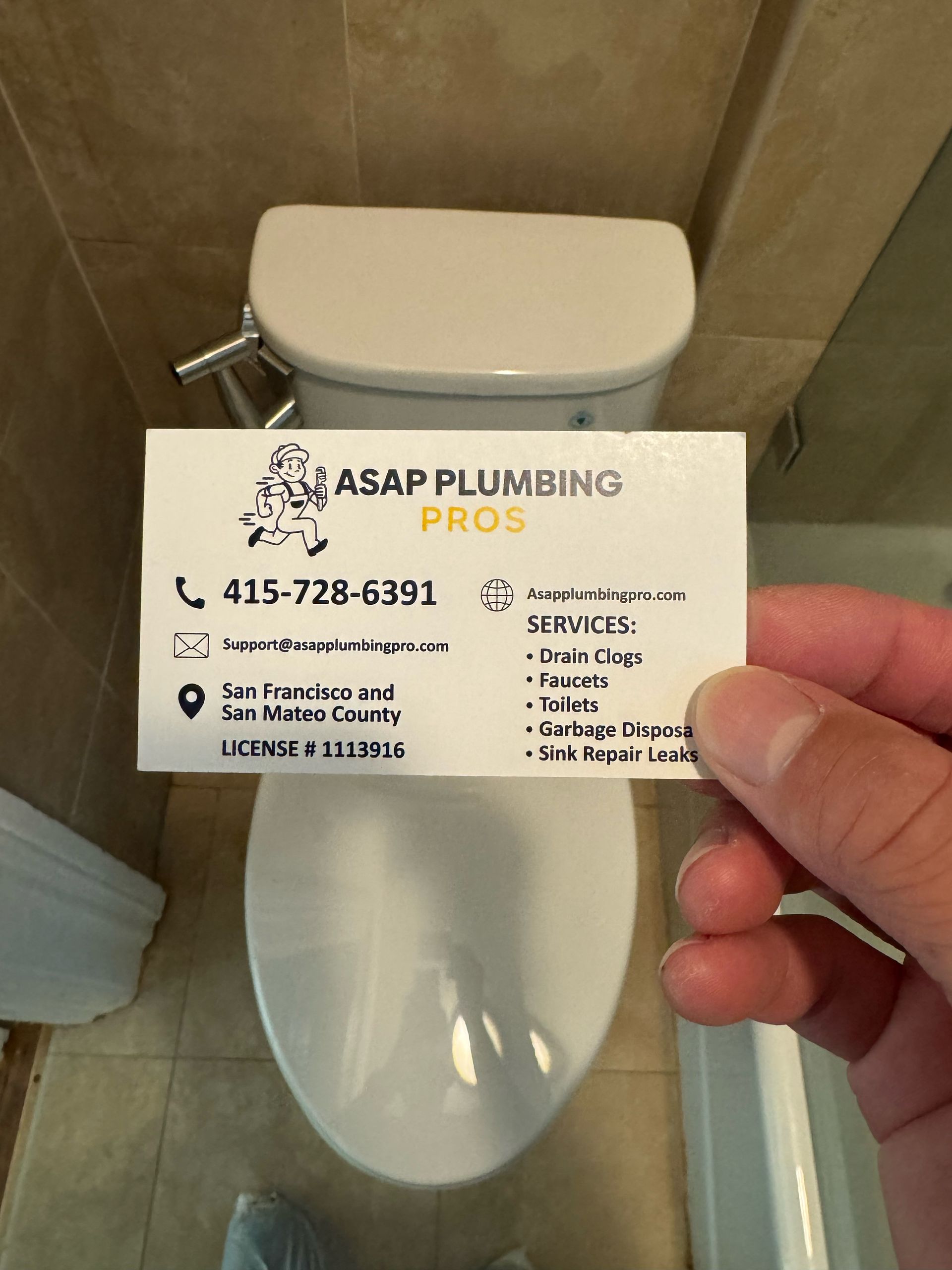 A person is holding a business card in front of a toilet.