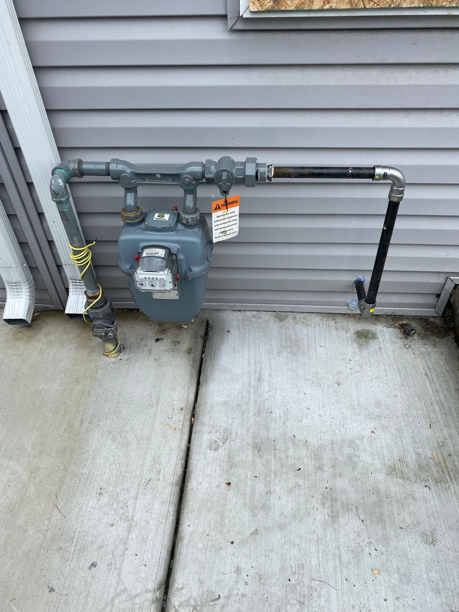 A hose is leaking water from a faucet on a wall.