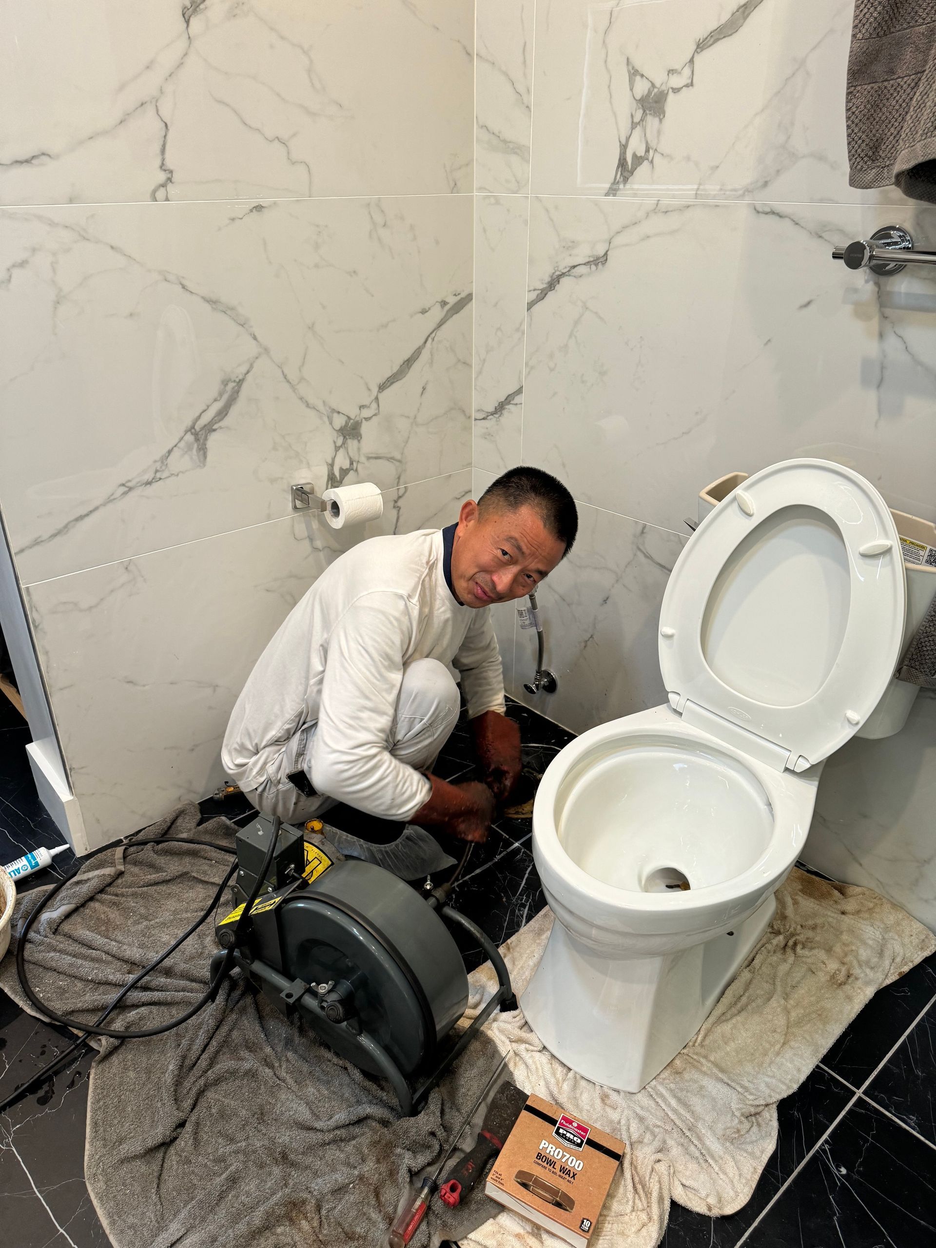 A man is working on a toilet in a bathroom.