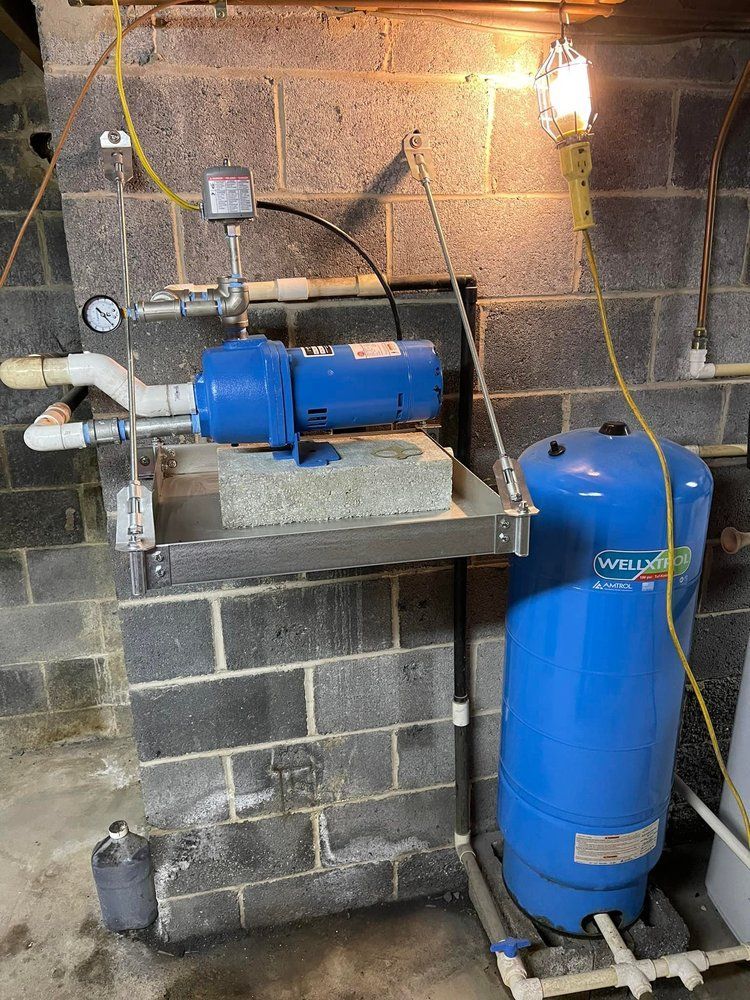 A blue water pump is sitting next to a blue tank in a basement.