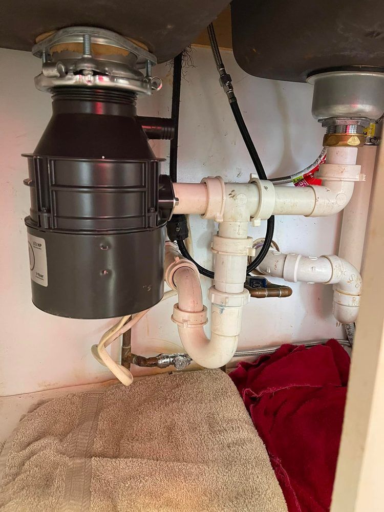 A plumber is fixing a toilet in a bathroom.