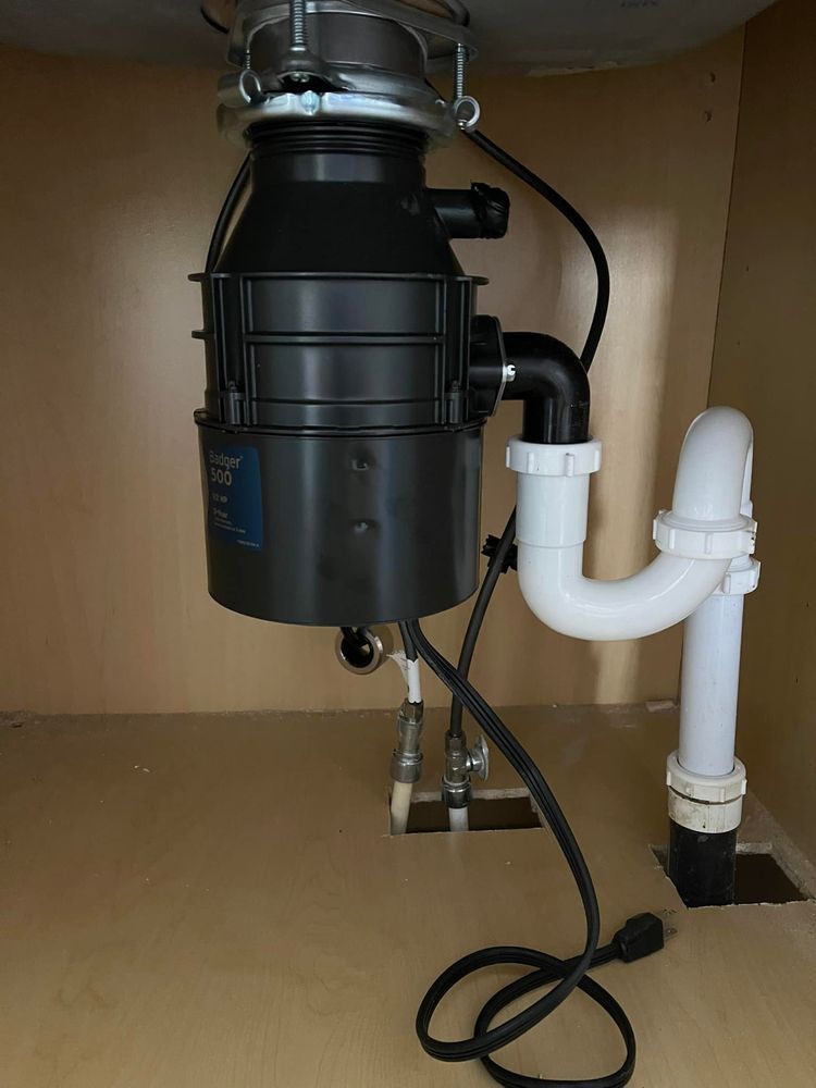 A garbage disposal is sitting under a sink in a cabinet.