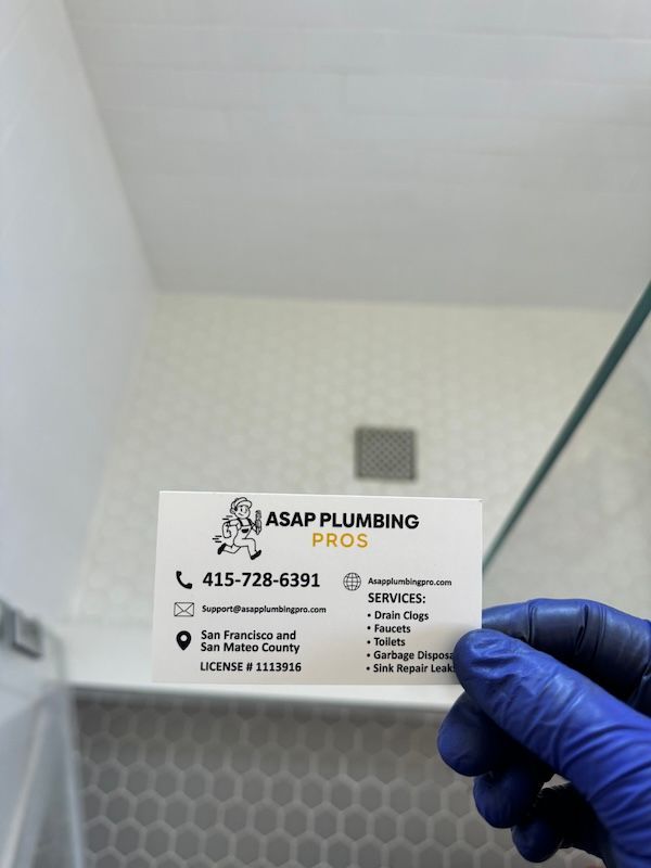 A person wearing blue gloves is holding a business card for asap plumbing pros