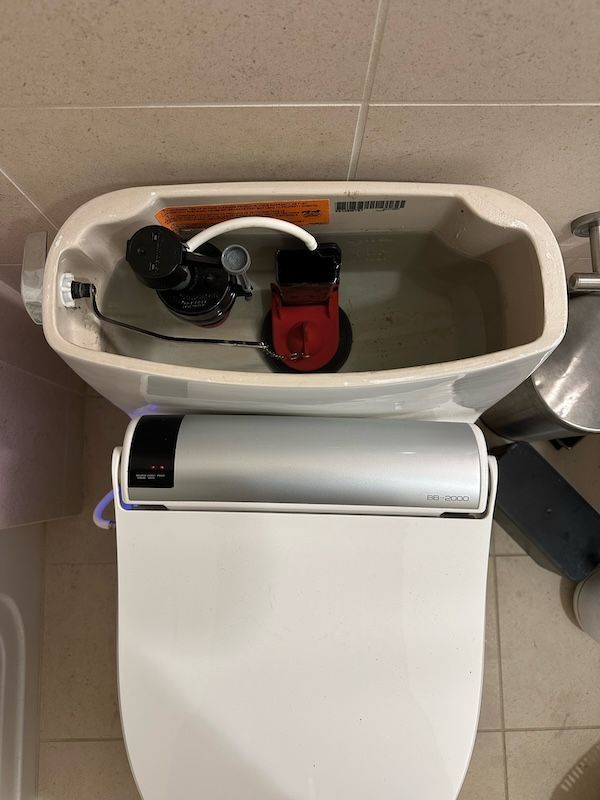 A toilet with a toilet seat and a toilet tank filled with water.