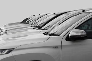 A row of white cars parked in a line, viewed from the side at an angle.