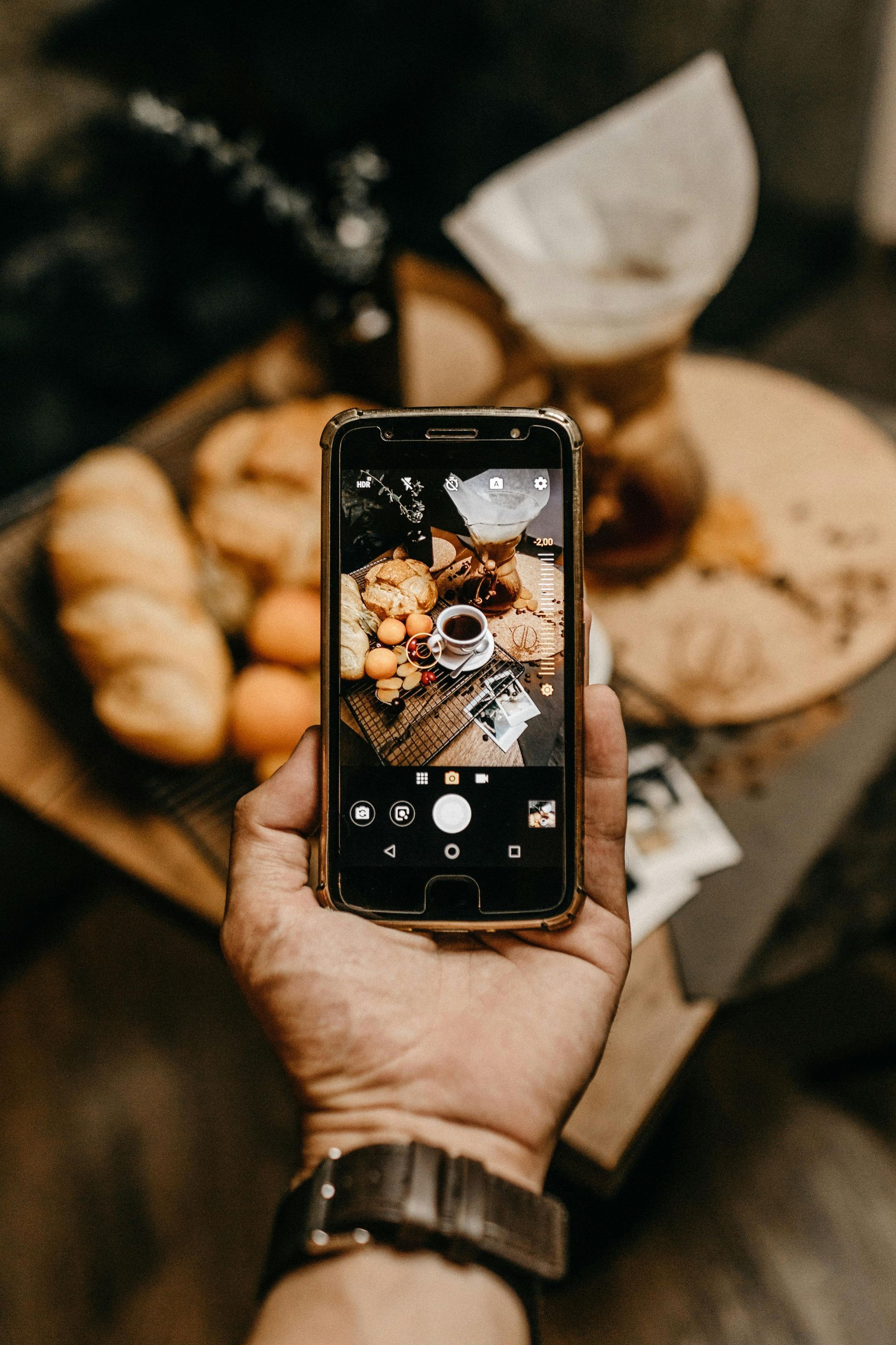 Foto com um celular tirando uma foto de pães.