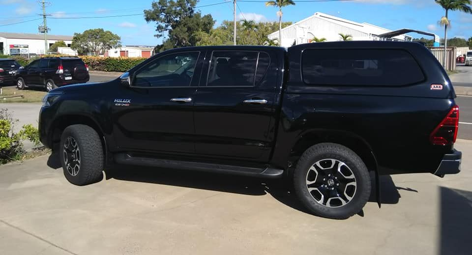 White Pickup Truck With Two Rooftop Tents Set Up in a Wooded Area — Stay on Track 4X4 Accessories in Gladstone Central, QLD
