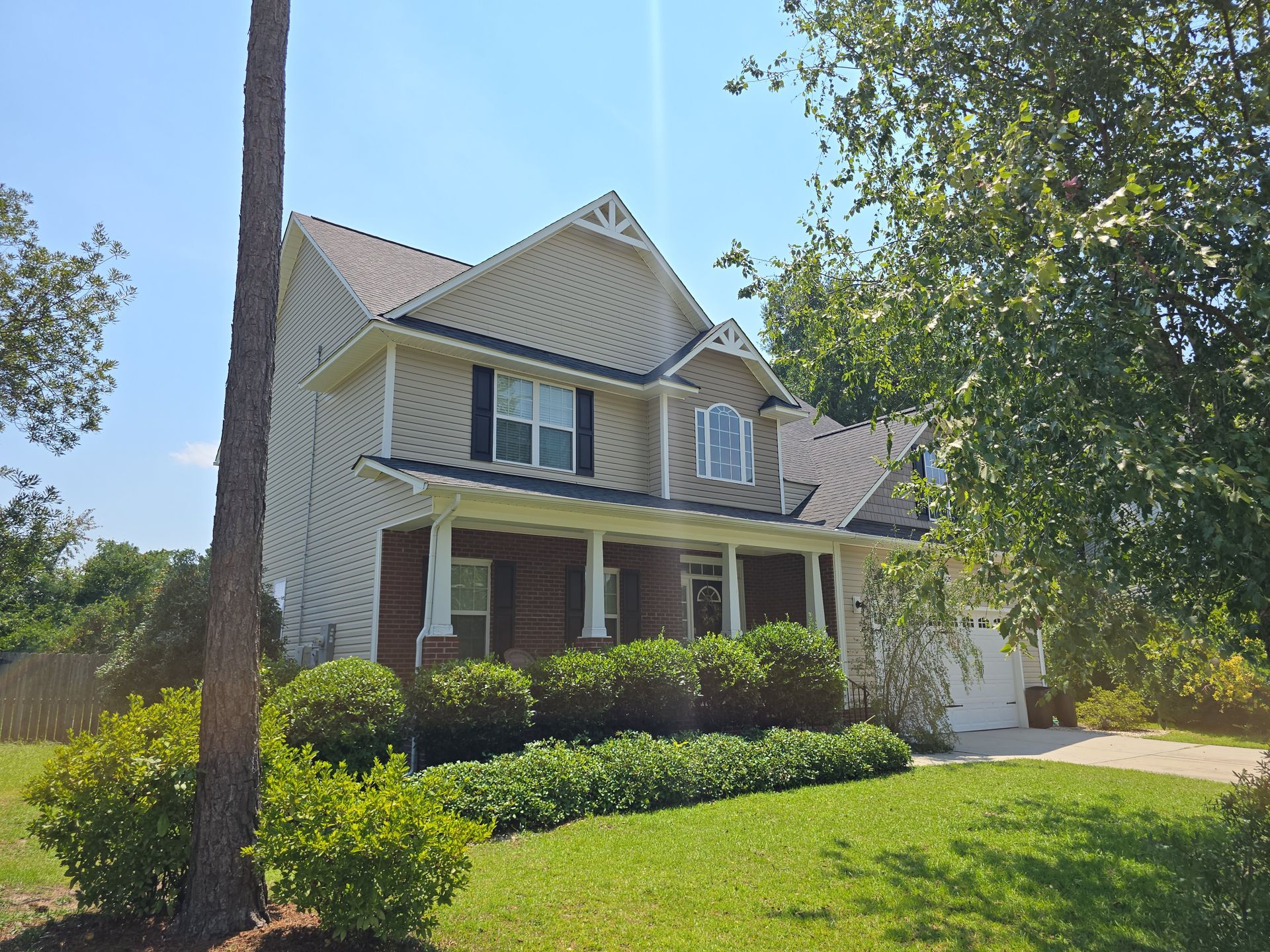 A large house with a large porch and a tree in front of it