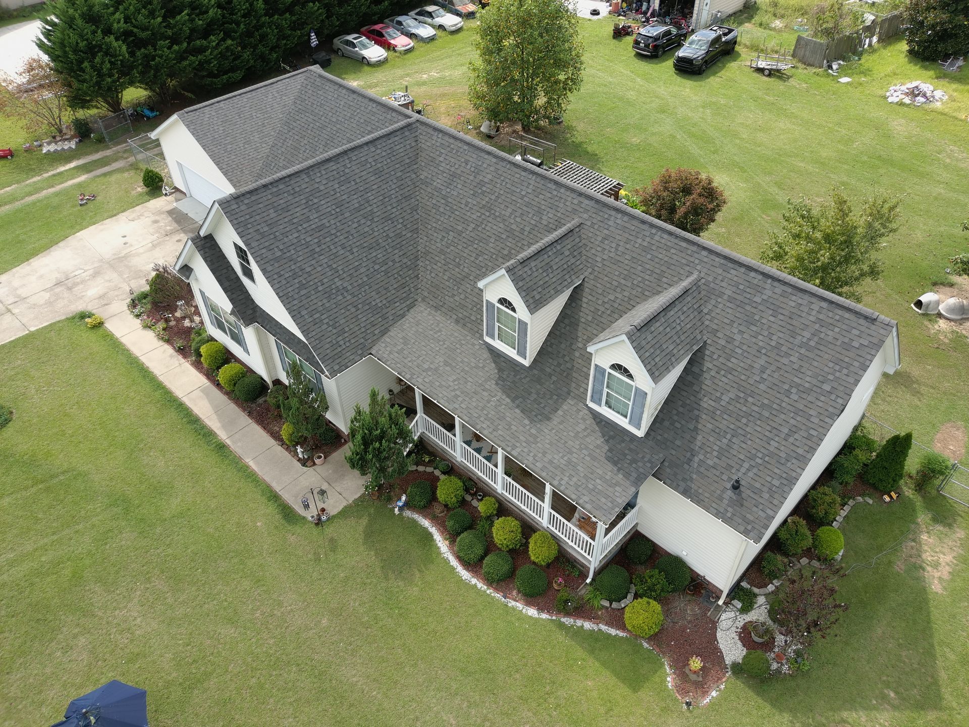 A yellow house with a black roof is sitting in the middle of a grassy field.