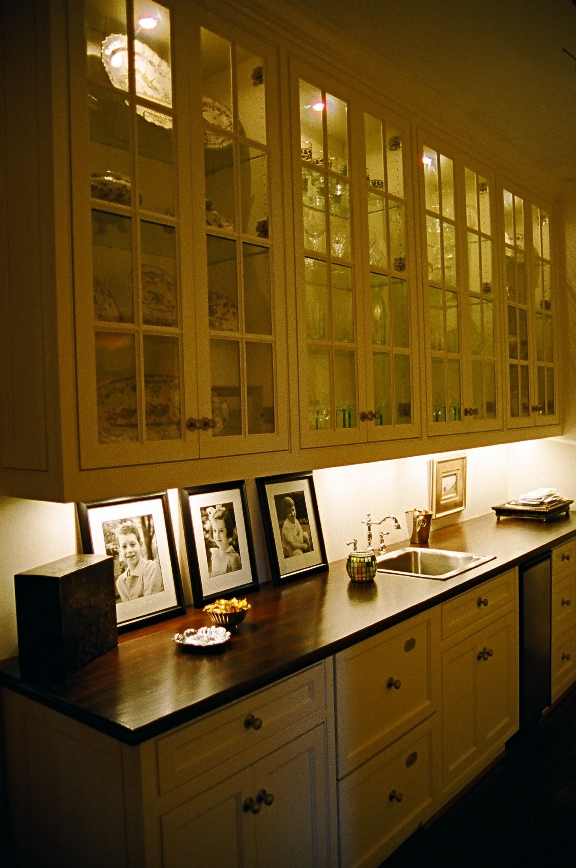 A kitchen with lots of cabinets and pictures on the counter