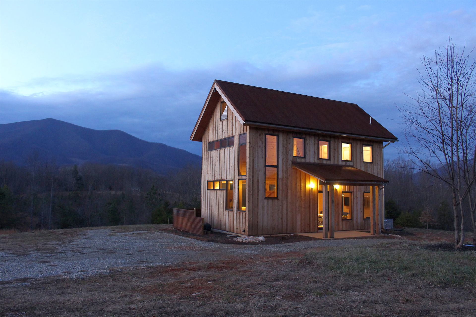 a small house in the middle of a field with mountains in the background