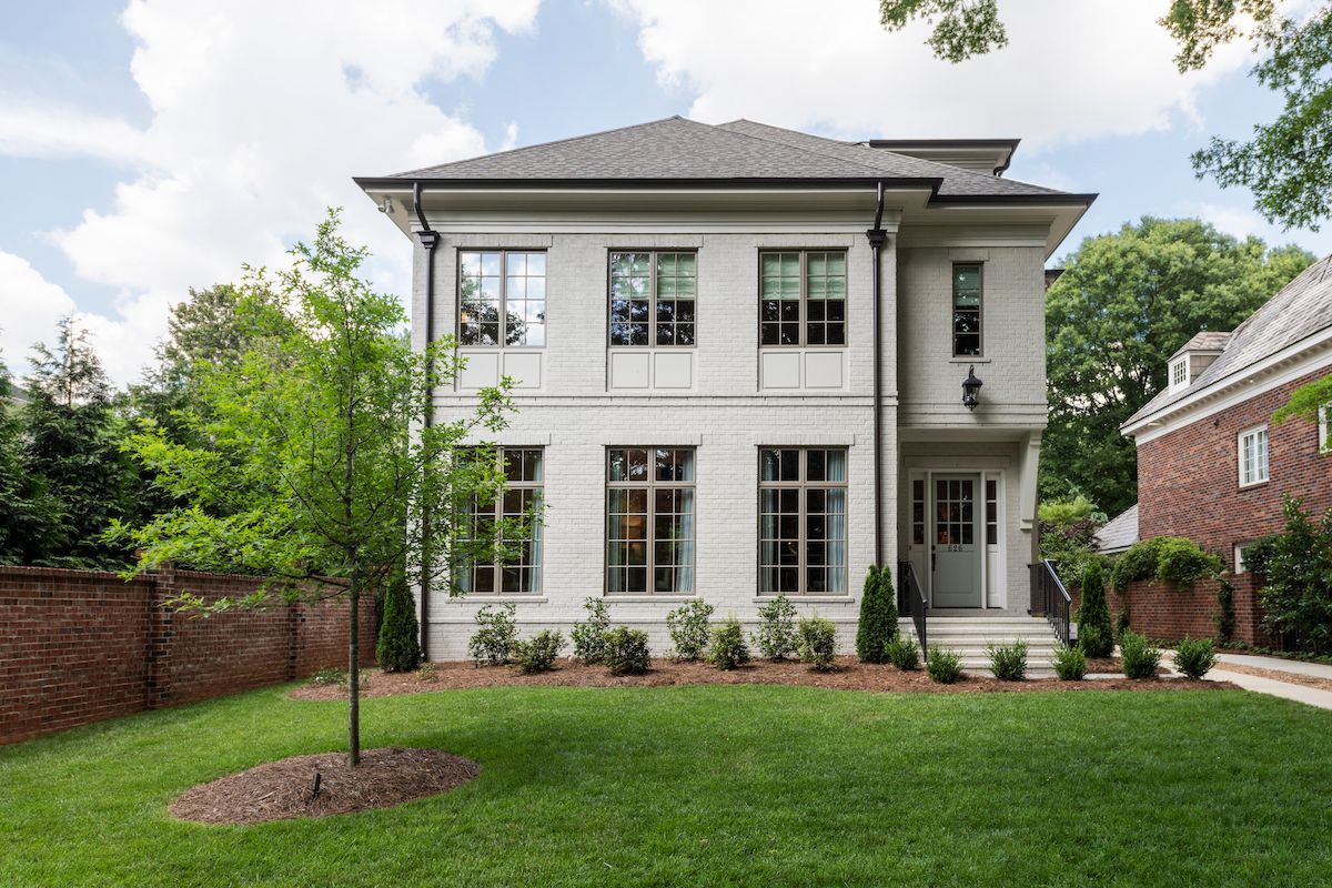 Modern house entrance with wood siding, black door and large window, dark steps in front