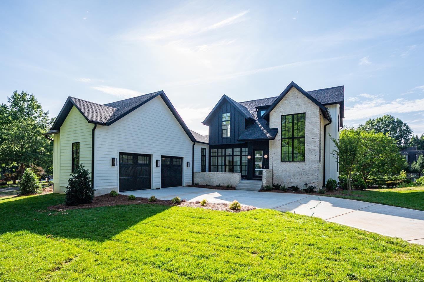 a large white house with a black roof is sitting on top of a lush green lawn .