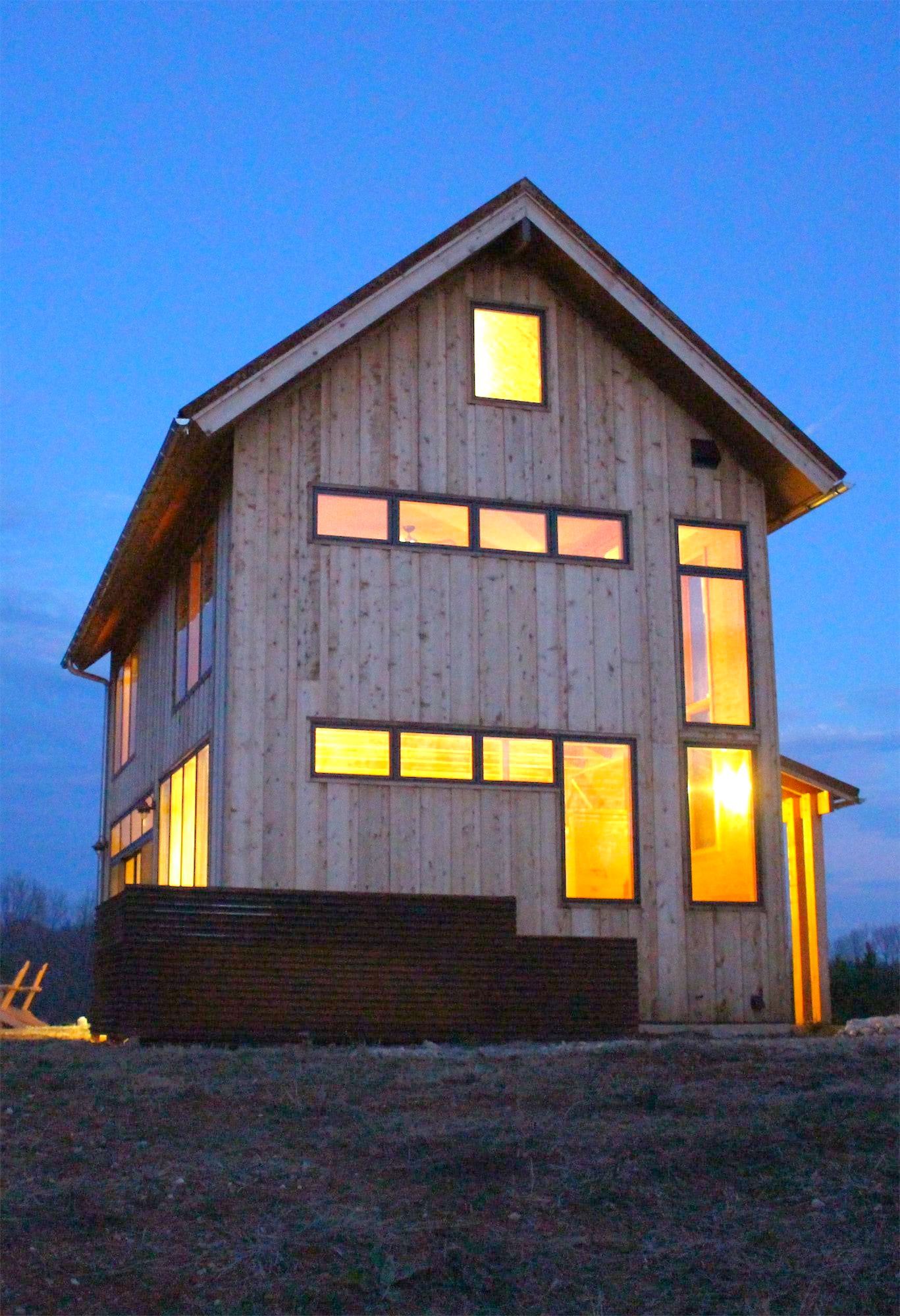 A house with a lot of windows is lit up at night