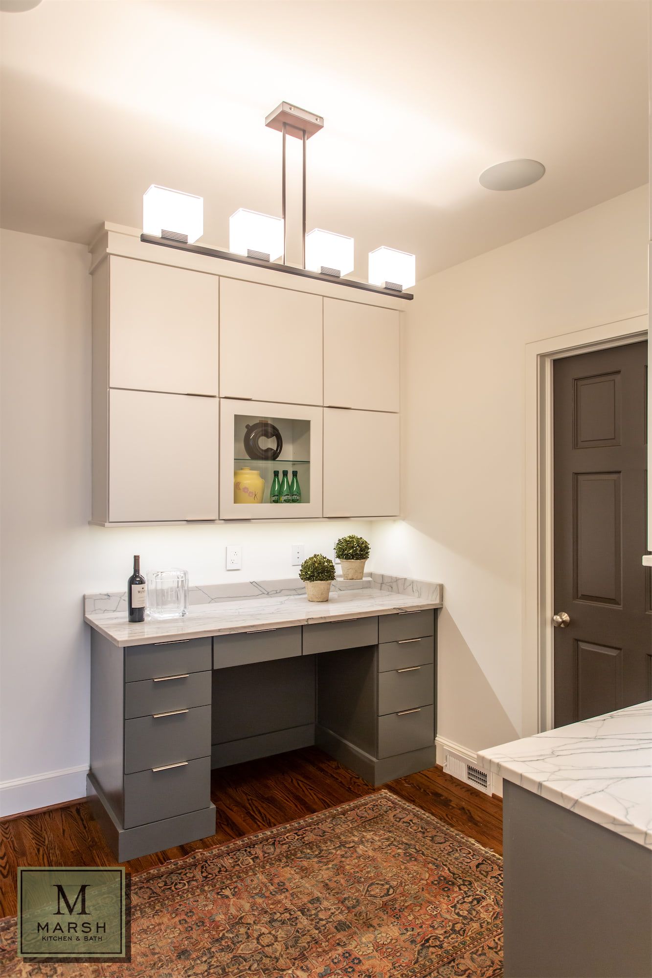 A room with a desk , cabinets , and a rug.