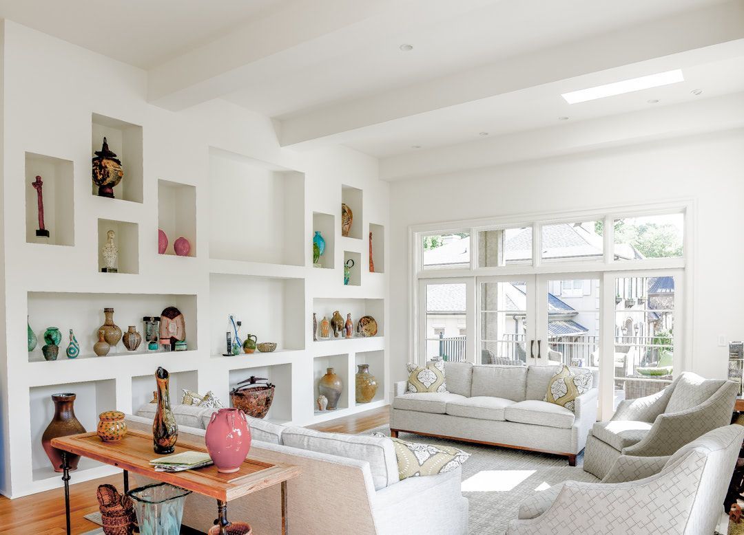 a living room with a couch , chairs , shelves and a table .