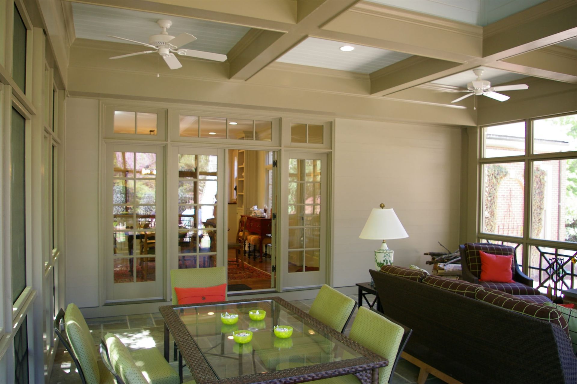 A screened in porch with a table and chairs and a ceiling fan