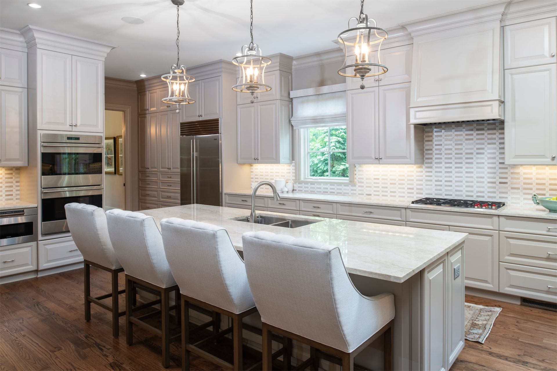 A kitchen with white cabinets , stainless steel appliances , and a large island.
