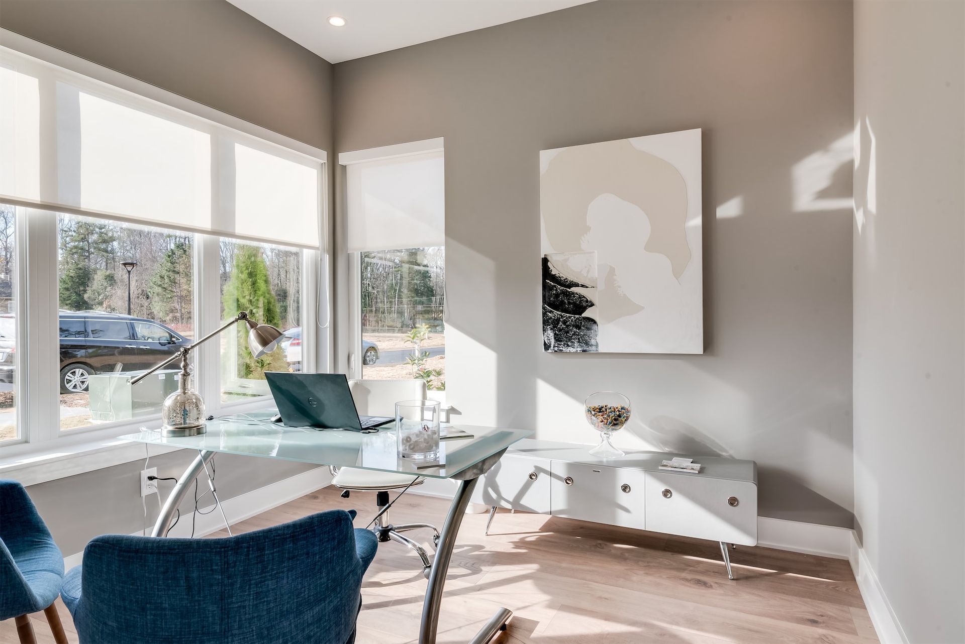 a home office with a desk , chairs , and a large window .