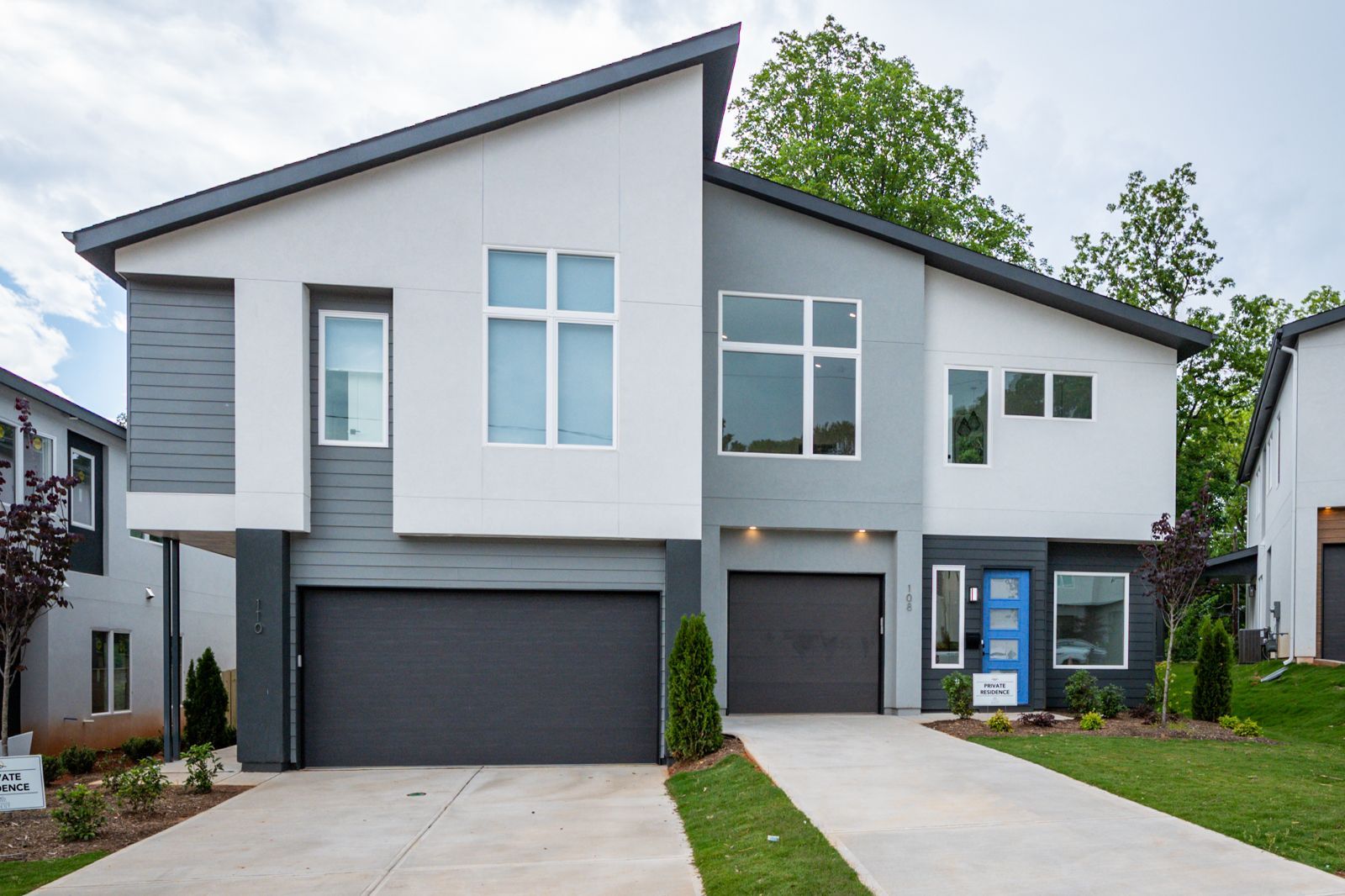 A modern house with two garages and a blue door