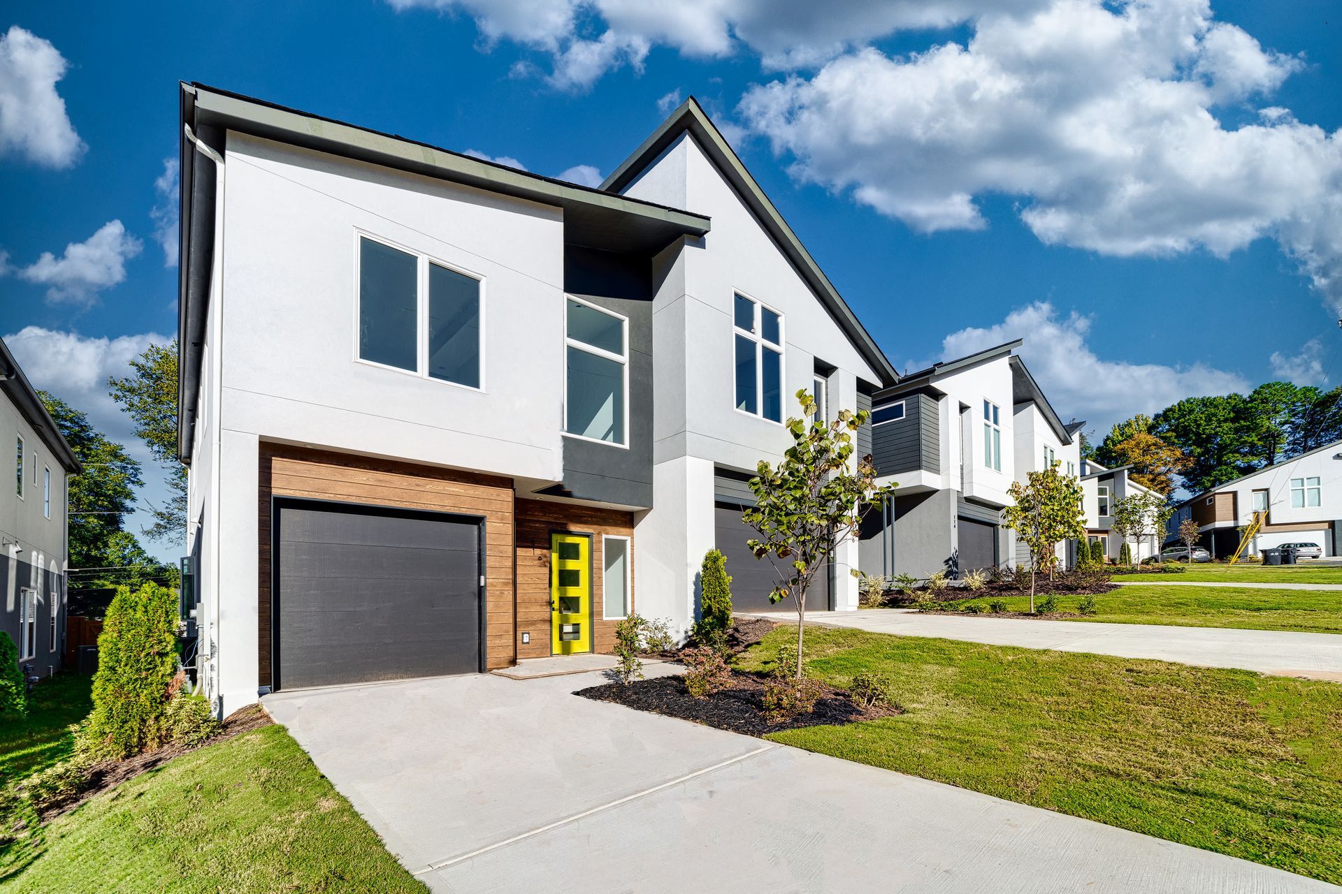 A white house with a black garage door and a yellow door.