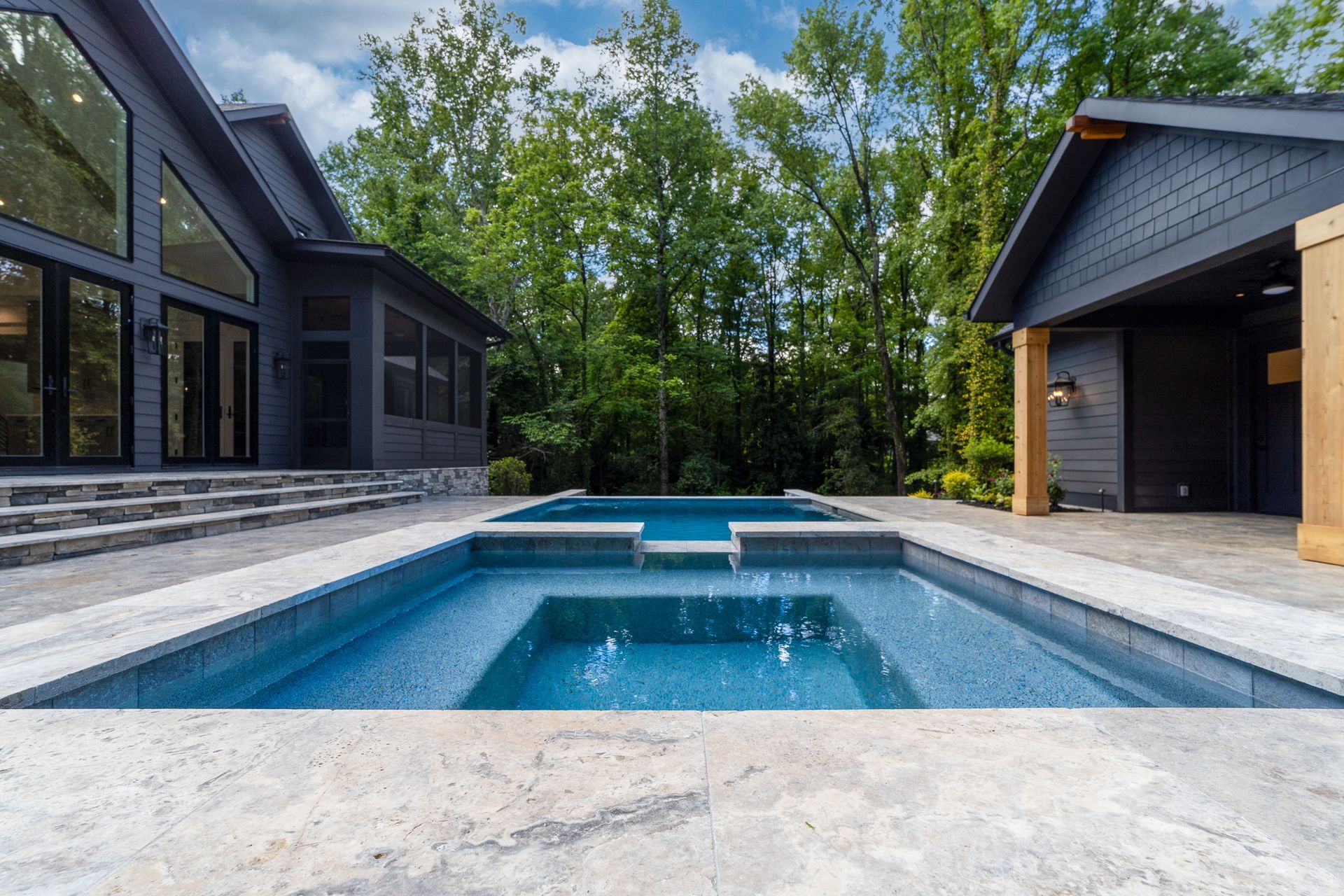 There is a large swimming pool in the backyard of a house.