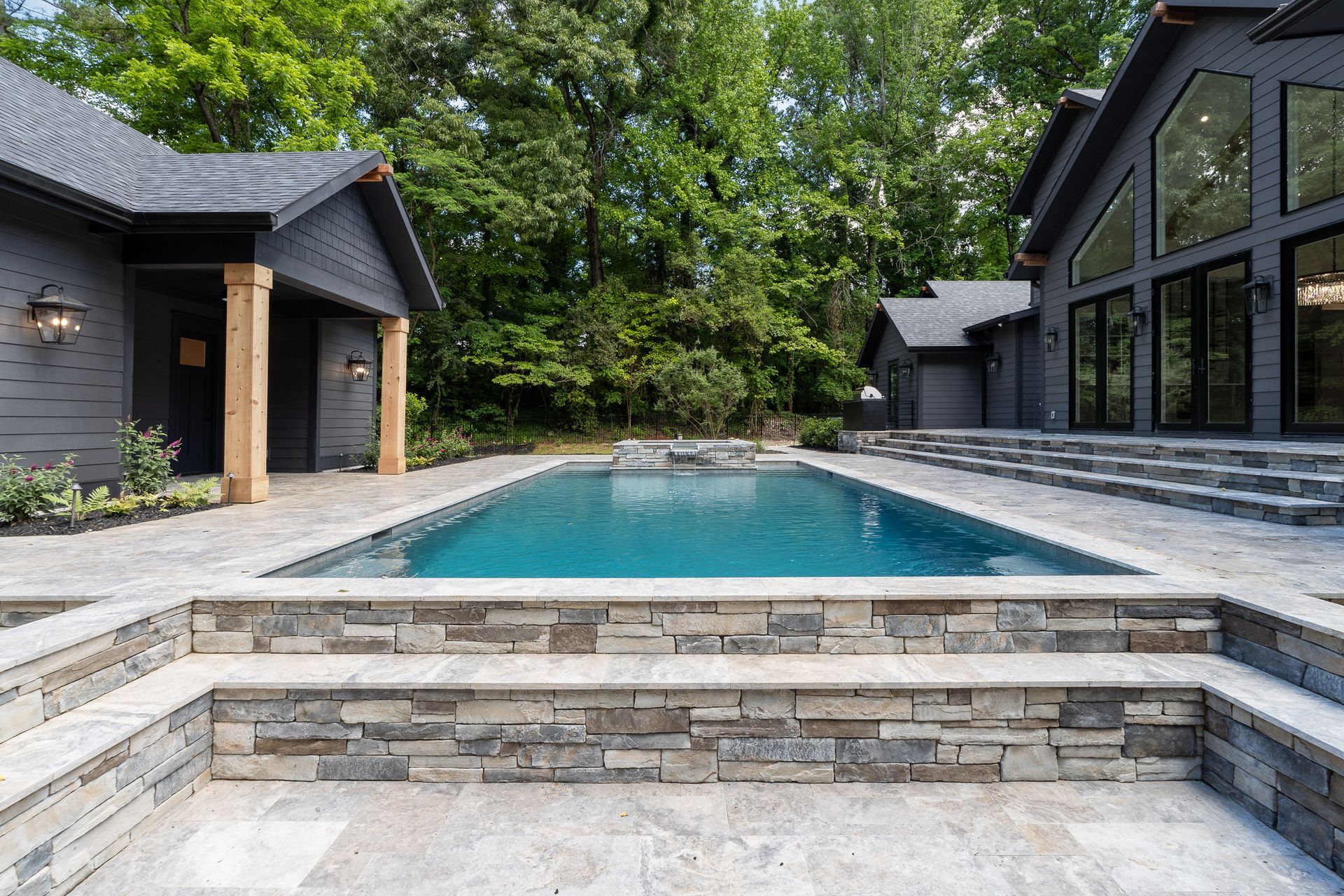 There is a large swimming pool in the backyard of a house.