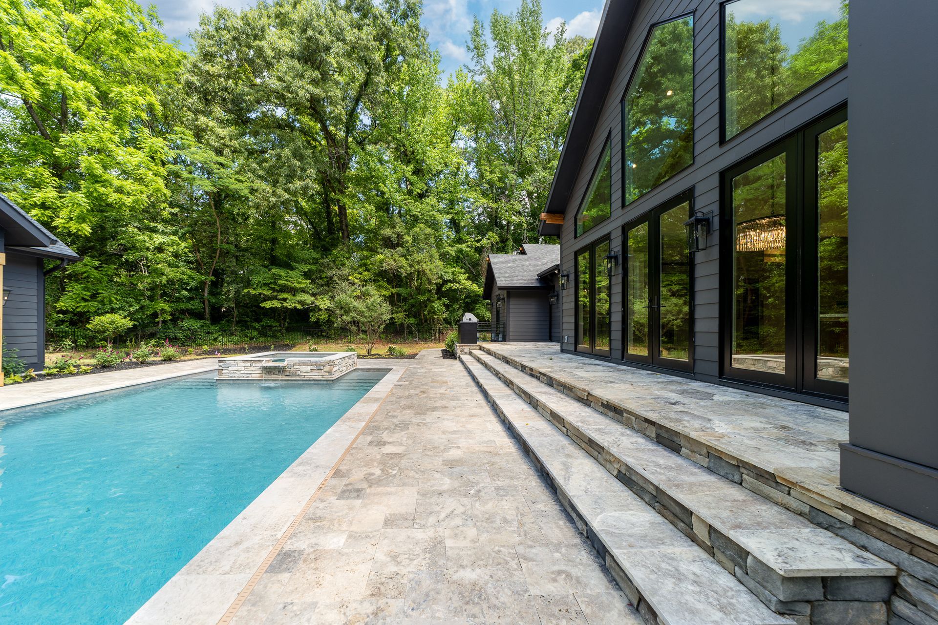 There is a large swimming pool in the backyard of a house.