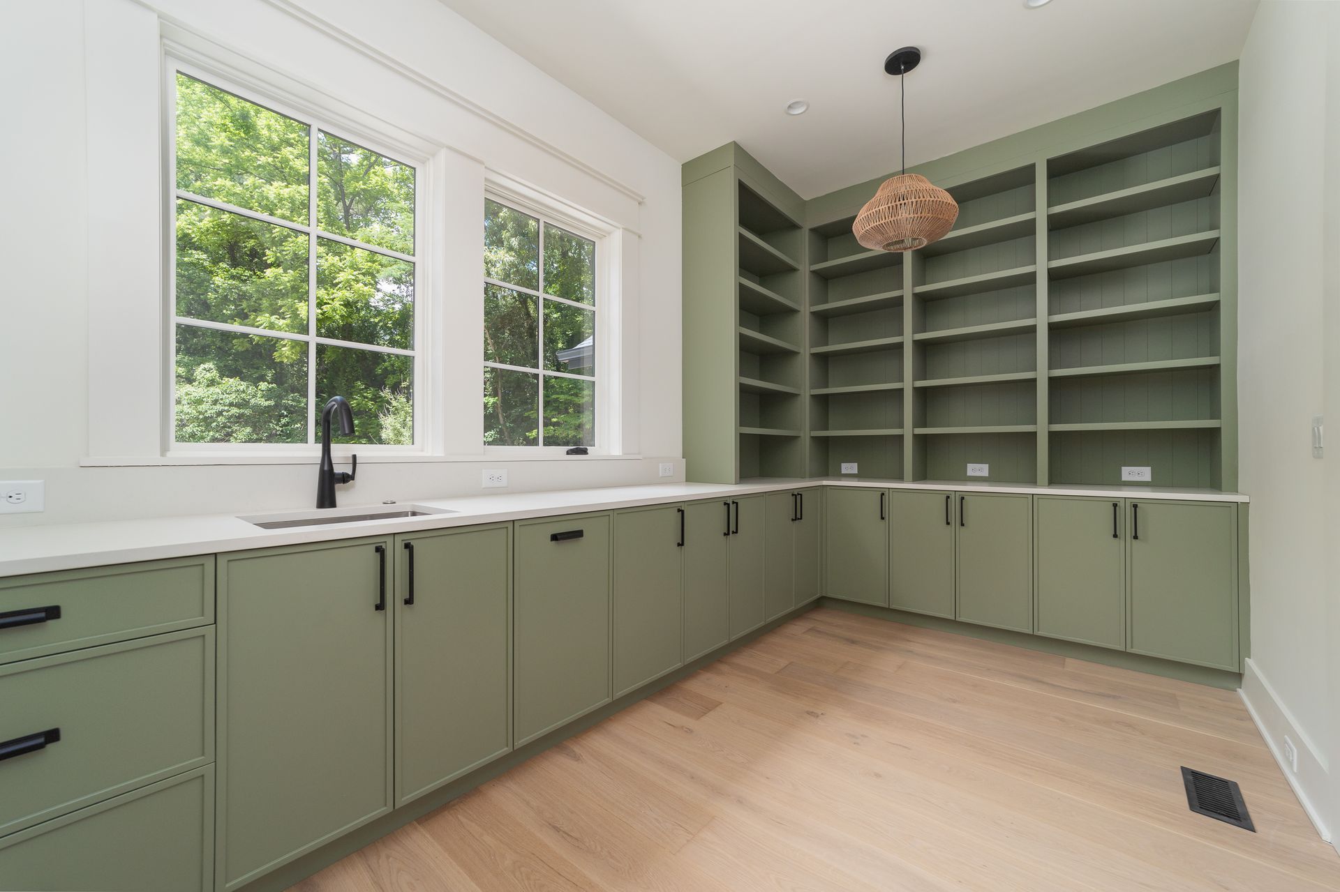 A kitchen with green cabinets and shelves and a sink.
