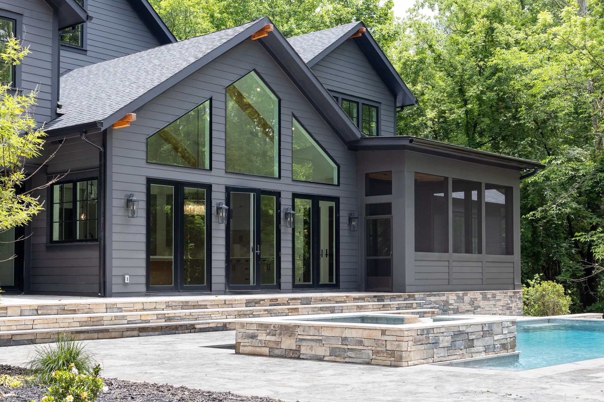 A large gray house with a screened in porch and a swimming pool.
