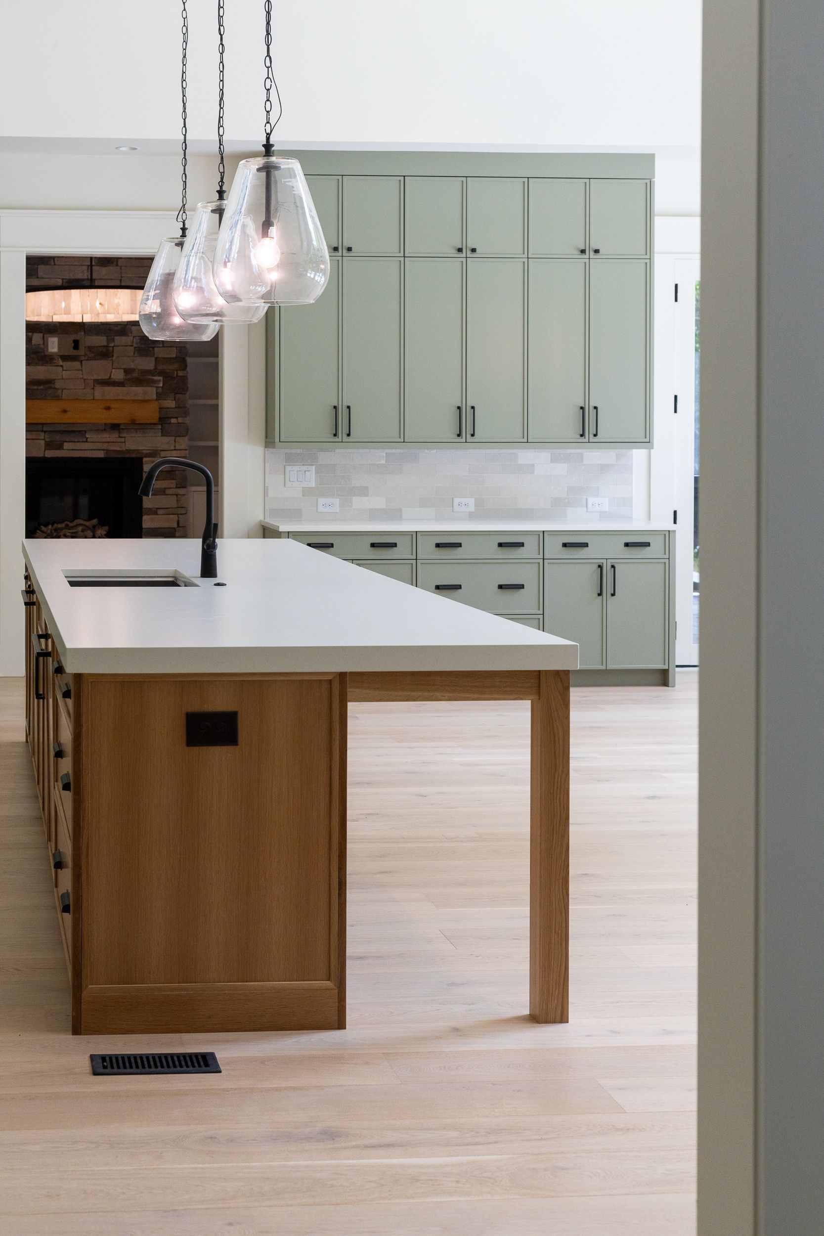 A kitchen with a large island and green cabinets