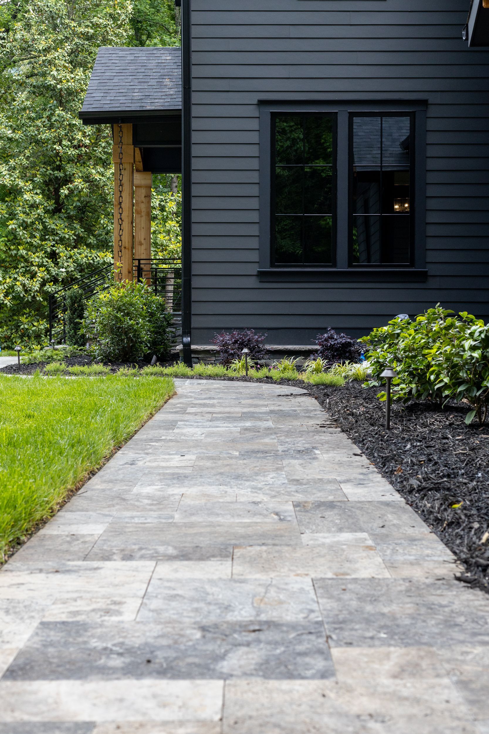 A stone walkway leading to a black house.